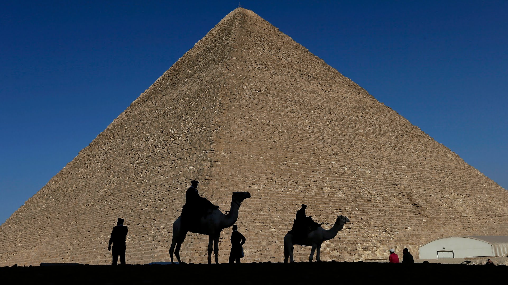 ARCHIVOS - Siluetas de policías se proyectan sobre la Gran Pirámide de Giza, Egipto, 12 de diciembre de 2012. Egipto develó el jueves 2 de marzo de 2023 una cámara de nueve metros de longitud dentro de la Gran Pirámide de Giza, la primera que se descubre en la cara norte de la estructura. (AP Foto/Hassan Ammar, File)