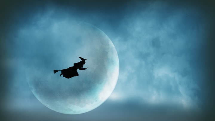 Silueta de una bruja volando frente a una luna en una escoba.